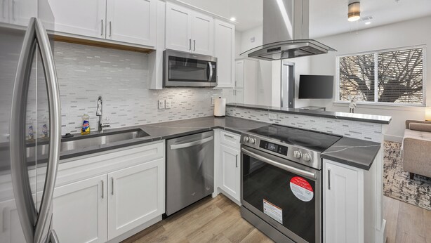 A modern kitchen with white cabinets, stainless steel appliances, a built-in microwave, and a large oven. - Perfect 1-bedroom townhome with rooftop in charming Fort Worth (Fort Worth)