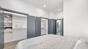 A bedroom with a large bed, grey wardrobe, and a walk-in closet. - Perfect 1-bedroom townhome with rooftop in charming Fort Worth (Fort Worth)