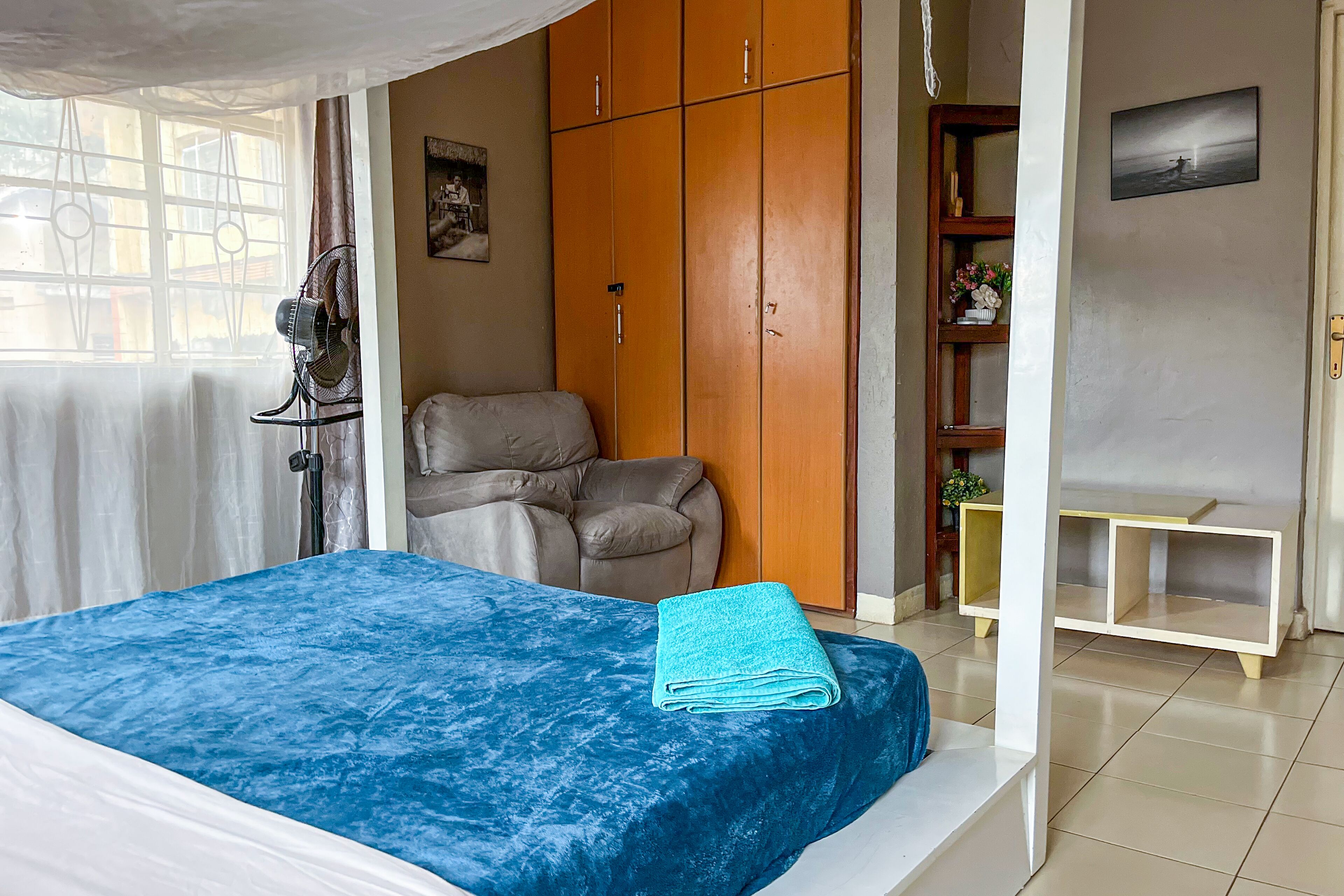 A bedroom with a bed, a wardrobe, a chair, and a small table.