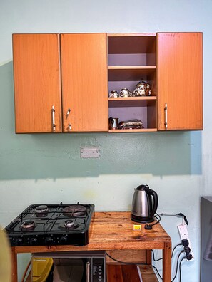Une cuisine avec des meubles de rangement en bois, une cuisinière à gaz, une bouilloire et une multiprise.
