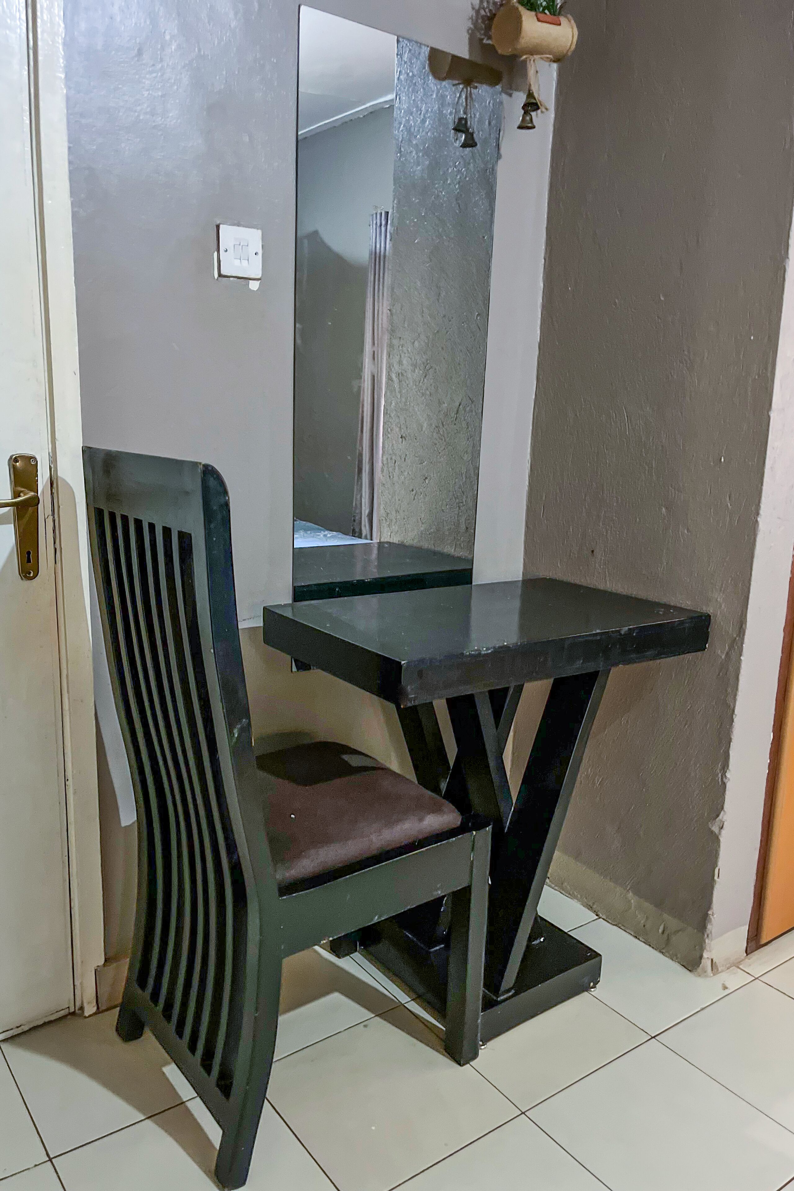 Un coin de pièce avec une chaise, une table et un miroir.