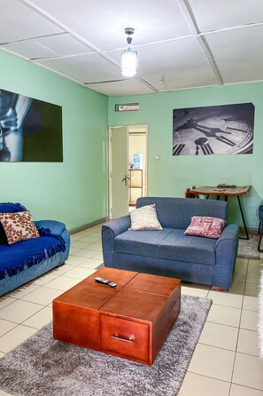 A living room with two sofas, a coffee table, and a painting on the wall. - Charming 2-bedroom apartment in enjoyable Kampala neighborhood free wifi (Kampala)