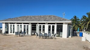 Un edificio con patio piastrellato, posti a sedere all'aperto e una zona coperta con porte in vetro.