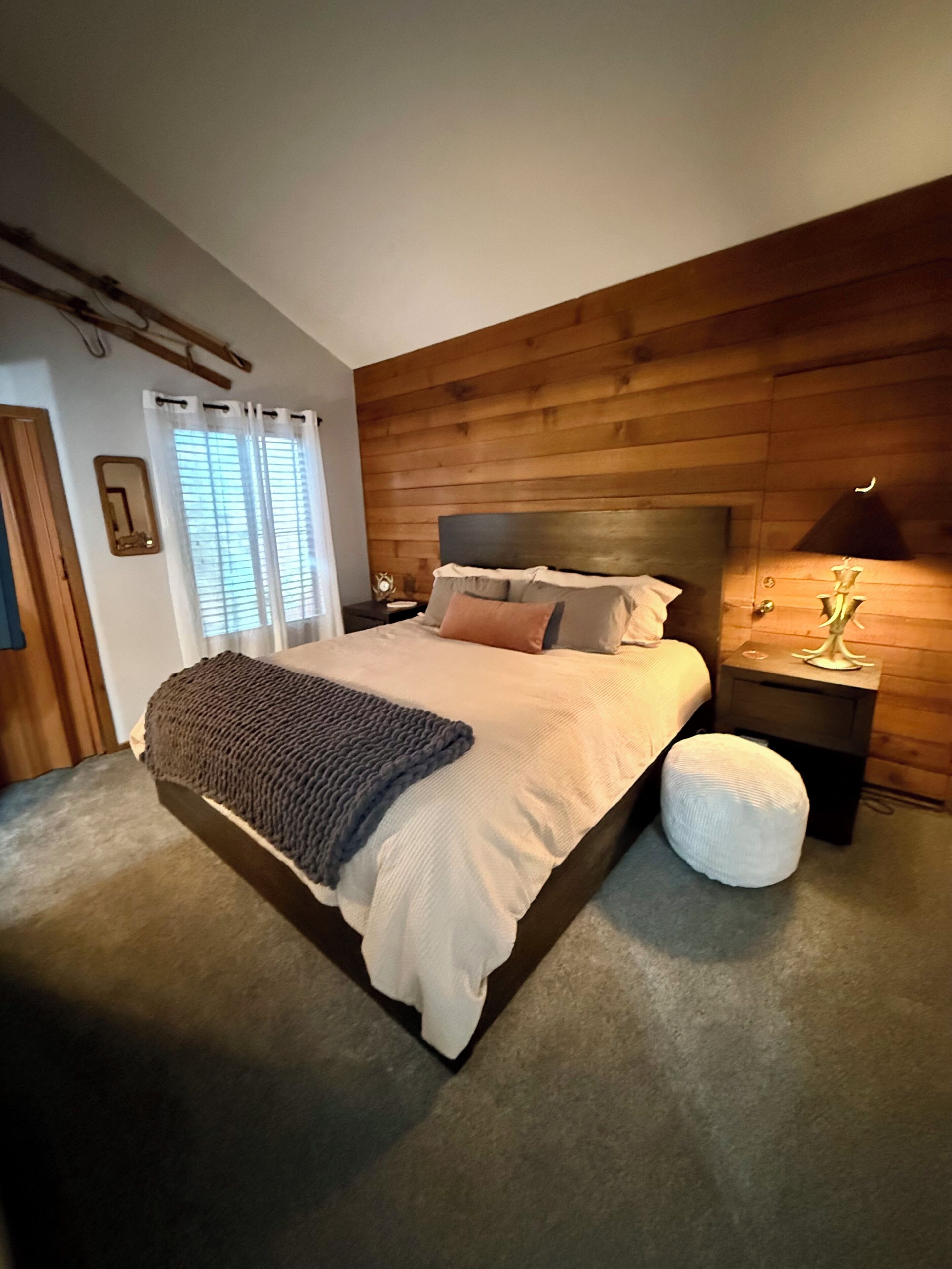 A bedroom with a large bed, a bedside table, a lamp, and a wooden headboard.
