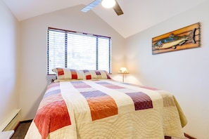A bedroom with a large bed, a window with blinds, a wall-mounted lamp, and a fish-themed artwork.