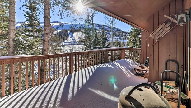 Una terraza de madera con vistas a montañas nevadas y árboles.