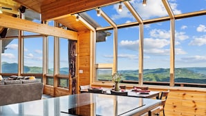 Une cuisine moderne dotée d’un grand îlot central, de murs en bois et de grandes fenêtres offrant une vue sur les montagnes.