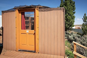 A wooden structure with a door, a number plaque, and a wooden deck.