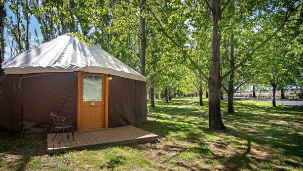 Una yurta de una habitación con una puerta, un pequeño porche y una silla.