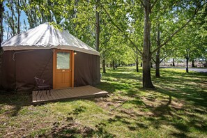 A single-room yurt with a door, a small porch, and a chair.