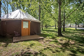 Una yurta de una habitación con una puerta, un pequeño porche y una silla.