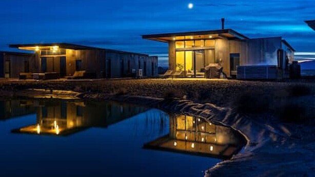 Una propietat moderna al costat del mar amb una piscina reflectant, un porxo cobert i una zona de seients a l'aire lliure.
