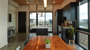 A modern kitchen with a large island, stainless steel appliances, and a view of the outdoors. - The Point at the Lakes - Cave B (Quincy)
