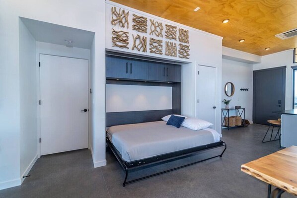 A modern bedroom with a bed, built-in cabinets, a wooden ceiling, and a small table. - The Lazy Vine Lakehouse at the Gorge (Quincy)