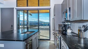 Eine moderne Küche mit großem Fenster, Edelstahlgeräten und Bergblick.