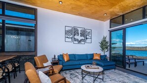 Ein modernes Wohnzimmer mit einem blauen Sofa, Ledersesseln, einem Couchtisch und Kunstwerken an der Wand.