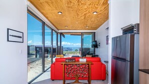 Une cuisine moderne avec un réfrigérateur en acier inoxydable, un canapé rouge et un plafond en bois.