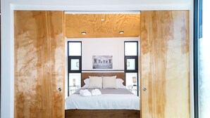 Une chambre avec un plafond en bois, un lit recouvert de draps blancs et un tableau encadré accroché au mur.