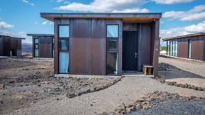 A modern, minimalist building with a flat roof, large windows, and a small entrance.