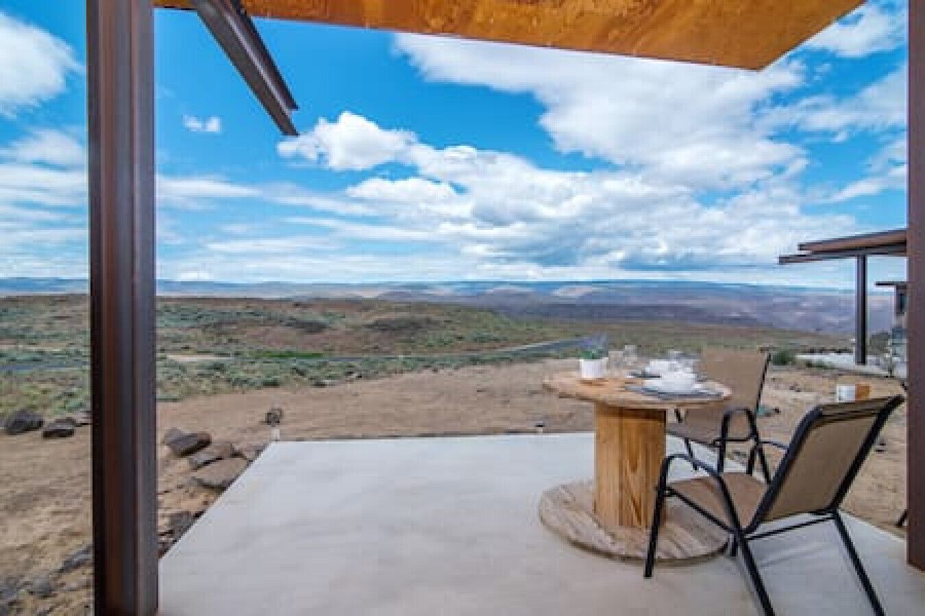 Un comedor con mesa y sillas, vista a un paisaje desértico y cielo despejado.