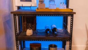 Een klein, donker houten wandrek met een computer monitor, een lamp en enkele andere spullen.