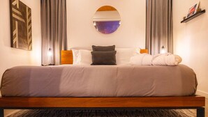 Een moderne slaapkamer met een groot bed, een ronde spiegel en een kamerbreed tapijt met dessin.