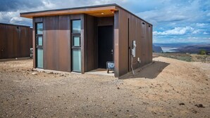 Een modern, laag gebouw met plat dak en grote ramen, gelegen in een droog, open landschap met heldere lucht.