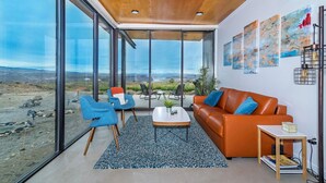 Un salon moderne doté de grandes fenêtres, d’un plafond en bois et offrant une vue sur le paysage.