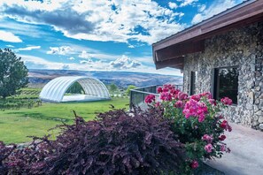 A stone building with a balcony, a greenhouse, and a view of a vineyard. - Sunset Splendor - Relax & UnWine 3B (Quincy)