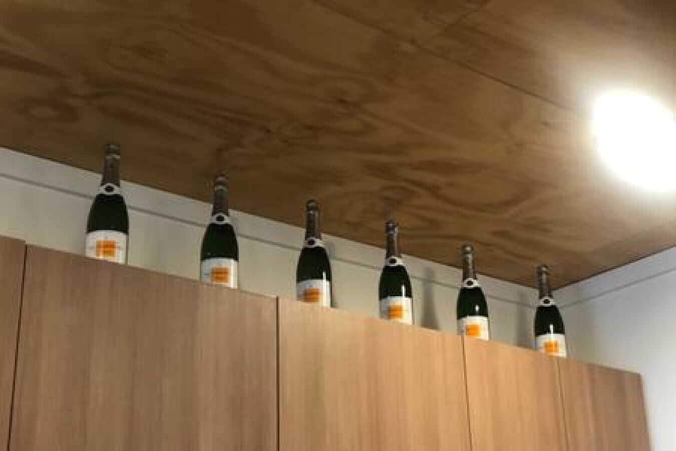 Ein Holzschrank mit fünf senkrecht angeordneten Weinflaschen.