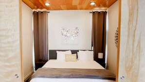 A bedroom with a bed, curtains, a headboard, and a wall decoration. - Wine Down in 3C at Cave B Ridge (Quincy)
