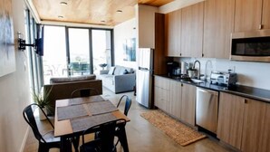 A modern kitchen with wooden cabinets, a dining area with a table and chairs, and a large window providing natural light. - Wine Down in 3C at Cave B Ridge (Quincy)