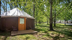 Una yurta de una habitación con una puerta, un pequeño porche y una silla afuera.