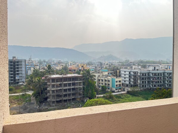 Un paysage urbain avec des immeubles de plusieurs étages, dont certains sont en construction, et une chaîne de montagnes en arrière-plan.