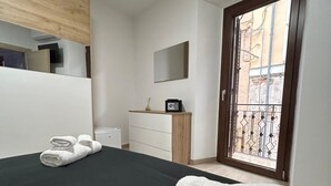 A bedroom with a bed, a dresser, a mirror, and a door leading to a balcony. - Double room with private bathroom and balcony (Spoltore)