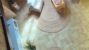 A cozy living room with a wooden ceiling, a sofa, a coffee table, a small side table, and a large window with curtains. - Cozy house in the heart of the Bastide with private courtyard and closed garage (Domme)