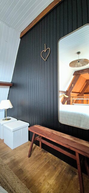 A modern room with dark wooden walls, a large mirror, a wooden bench, and a white bedside table with a lamp. - Cozy house in the heart of the Bastide with private courtyard and closed garage (Domme)
