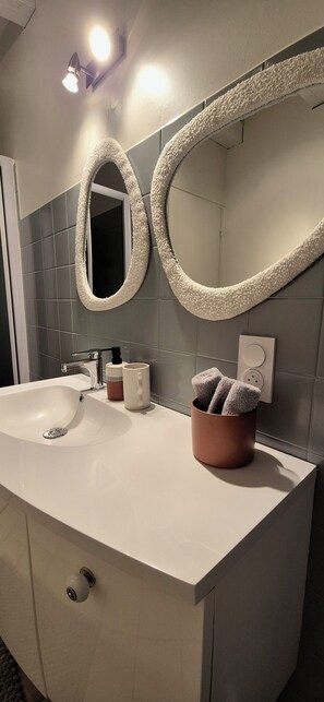 A modern bathroom with a white sink, two mirrors, a towel rack, and a cup holder. - Cozy house in the heart of the Bastide with private courtyard and closed garage (Domme)