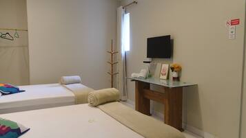 A hotel room with two beds, a TV, a small table with a vase, and a 'no smoking' sign.