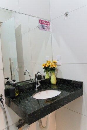 Baño con lavamanos, espejo, grifo y un letrero de precaución.
