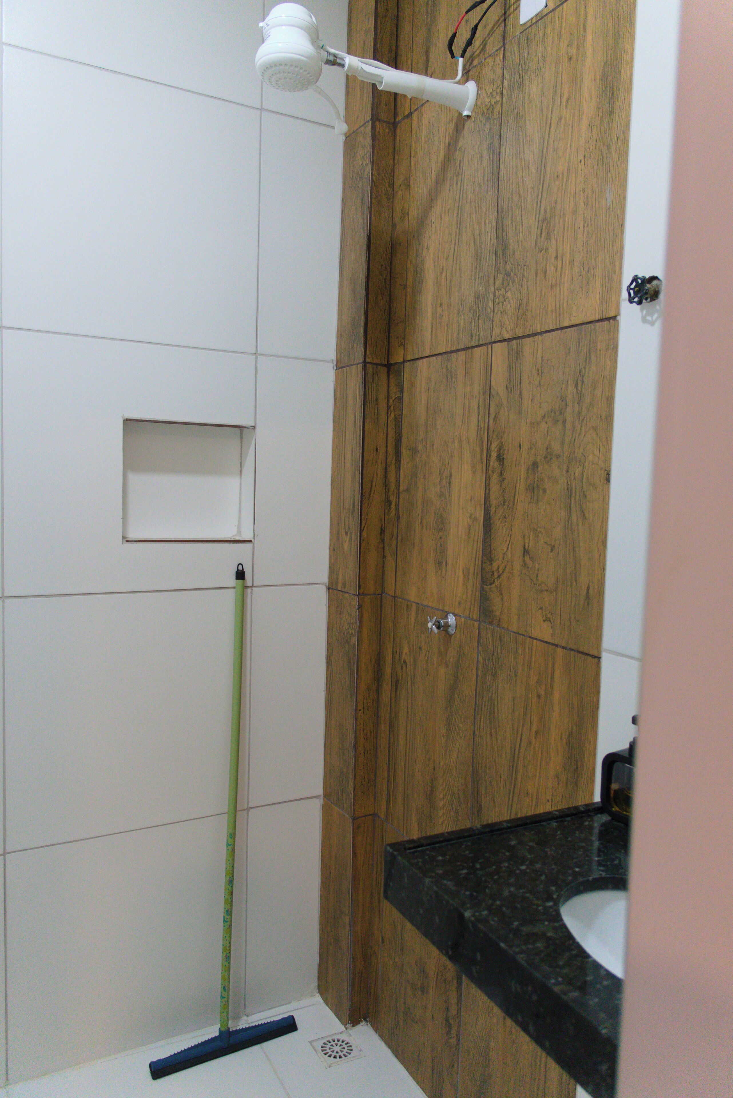 A bathroom with a shower, a wooden vanity, and a white sink.