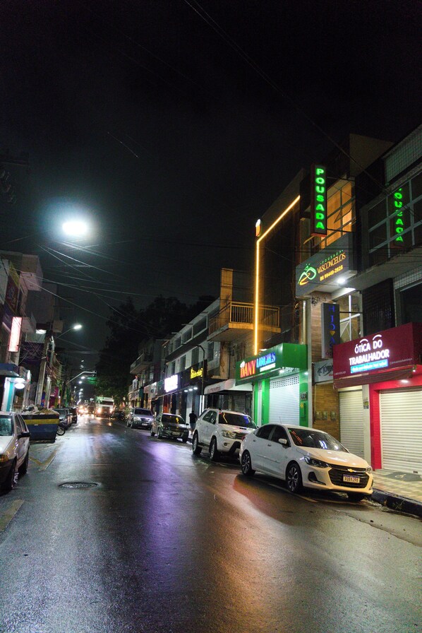 Una calle iluminada de noche con edificios y coches estacionados.