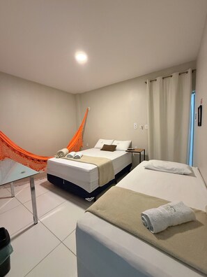 Una habitación de hotel con dos camas, una mesa de vidrio y una hamaca.