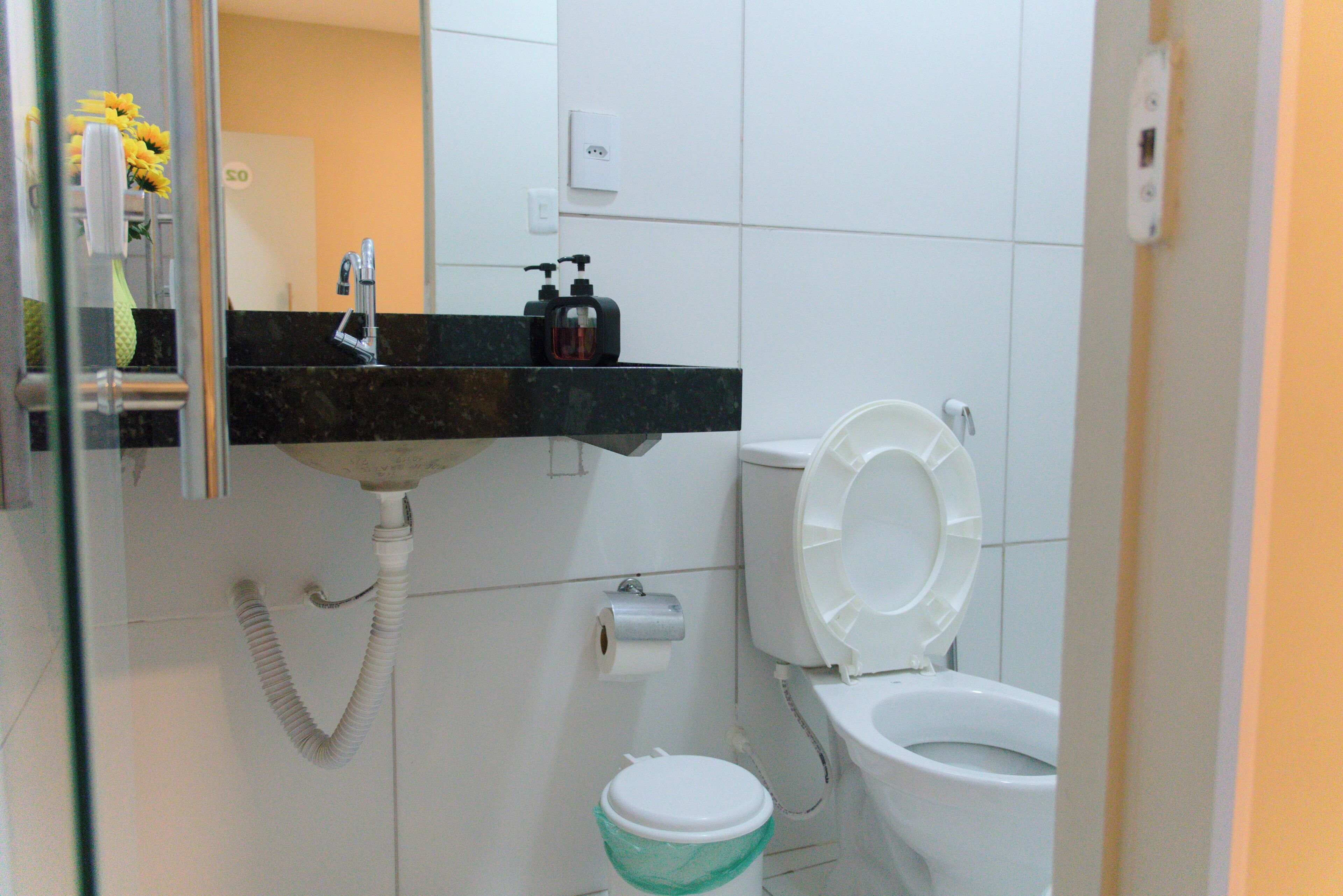 A bathroom with a toilet, sink, and a hand dryer.