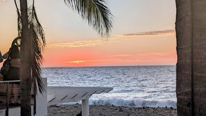 A beach with a white lounge chair and palm trees. - Charming oseanfront, New appartment (Puerto Vallarta)