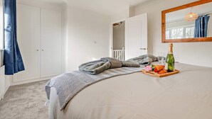 Una camera da letto con un letto, una testiera in legno, uno specchio, una finestra con tende e un vassoio per la colazione sul letto.