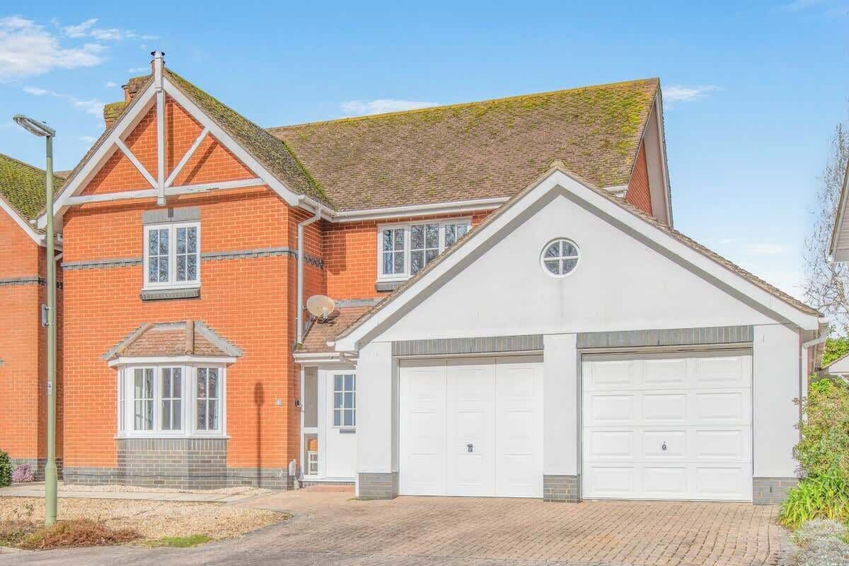 A two-story house with a garage, brick exterior, and a small front porch.