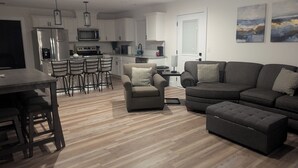 A modern living room with a grey sofa, a small armchair, and a dining area with a table and chairs. - Located in the Eli community of Russell Springs near Beautiful Lake Cumberland. (Russell Springs)
