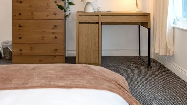 Ein Schlafzimmer mit einem hölzernen Schminktisch, einem Schreibtisch und einem Bett.