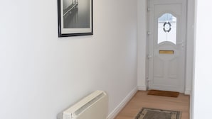 Ein Flur mit einer weißen Tür, einem Heizkörper und einem gerahmten Bild an der Wand.